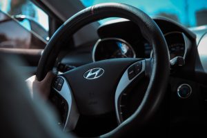 Close-up of a person's hand gripping a steering wheel with the Hyundai logo in the center, symbolizing the impact of driving habits on Hyundai ix35 fuel consumption.