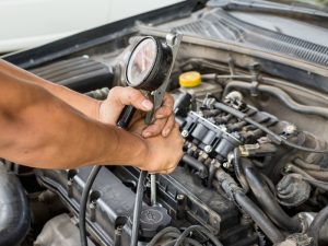 Mechanic using a pressure gauge on Hyundai engine to diagnose potential engine failure.