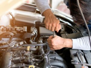 Mechanic fixing a car engine using tools, addressing possible Kia engine problems during maintenance work.