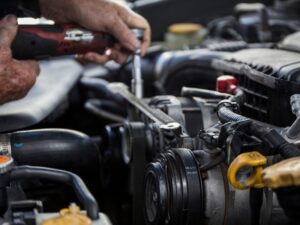 Car mechanic performing reconditioning process on car engine in garage.