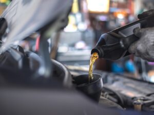 A mechanic pours oil into a funnel, preventing potential engine overheating.