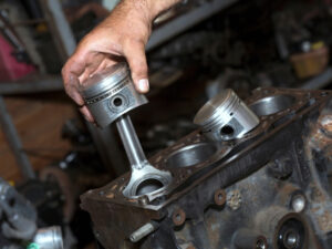 Close-up of a faulty Kia engine piston and connecting rod, showing damage.